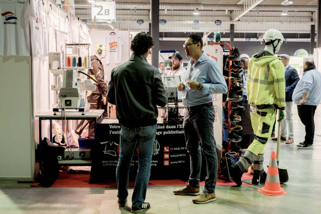 Deux hommes échangent devant un stand - Forum SST 2024
